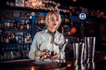 Girl barman formulates a cocktail on the taproom