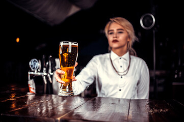 Charming woman bartender formulates a cocktail while standing near the bar counter in nightclub
