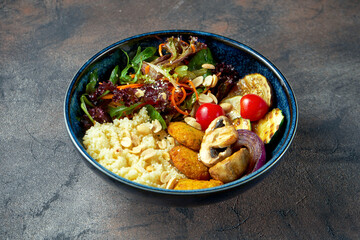 Buddha bowl with falafel, couscous, grilled vegetables in a blue plate. Selective focus