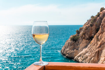 A glass of white wine. Wine against the backdrop of the sea coast and a sunny summer beach. Wine tasting and relaxation at the resort