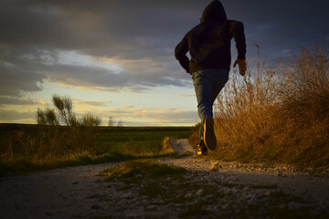 Mesmerizing shot of a male in a black hoody running through the forest