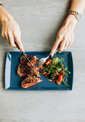woman cuts juicy steak on a plate