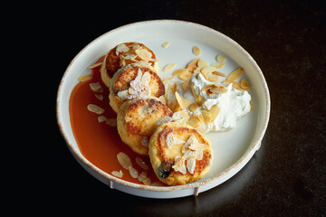 An ideal breakfast - Cottage cheese pancakes with caramel, almonds and cream sauce in a white plate. Ukrainian syrniki