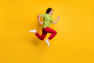 Full length body size side profile photo of jumping man running fast smiling isolated on vivid yellow color background
