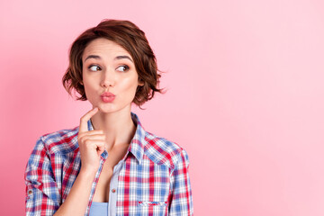 Photo portrait of curious pouting woman touching face chin with finger looking at blank space isolated on pastel pink colored background