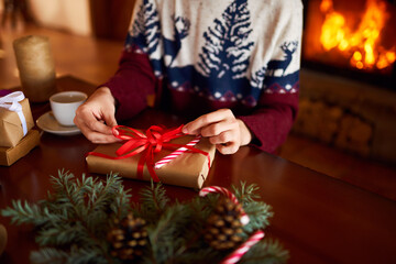  Men's hands hold Christmas present.  Man using red ribbon, green fir tree twig to create Christmas gift. Wintar holiday. 