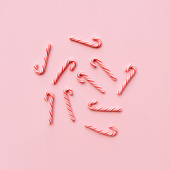 Top view of Christmas candy canes on pastel pink background. Holiday festive celebration greeting card with copy space to addng text