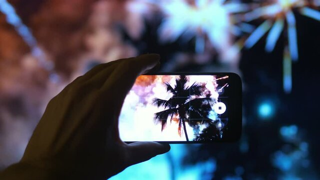 Person taking picture of the fireworks exploding show in tropical island in 4K
