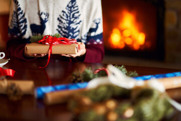  Men's hands hold Christmas present.  Man using red ribbon, green fir tree twig to create Christmas gift. Wintar holiday. 