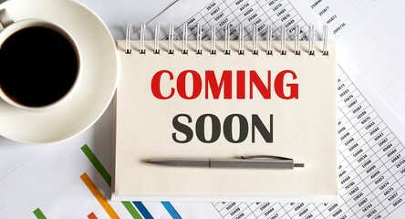 COMING SOON text written on a notebook with pen and chart