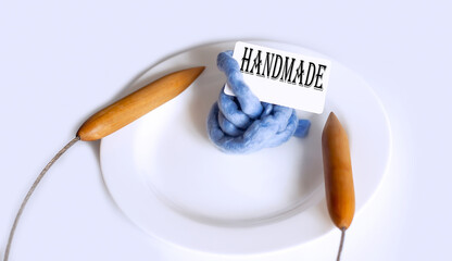 Text HANMADE with big knitting needles on plate