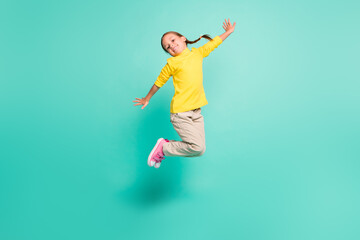 Fototapeta na wymiar Full size photo of happy girl jump in air wear yellow turtleneck white pants isolated on shine teal color background