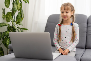 Little girl using video chat on laptop at home. Space for text