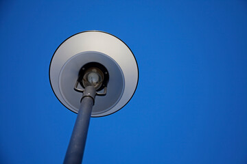 white street lamp seen from below with blue sky