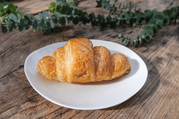 Croissant in white plate on a wooden table