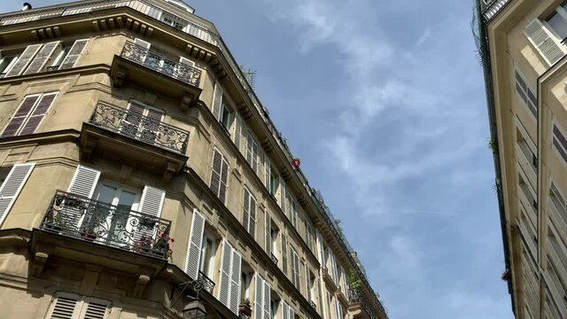 Bottom view footage of historical, traditional buildings showing French / Parisian architectural style in "Le Marais" area of Paris. It is a sunny summer day. Camera moves forward.