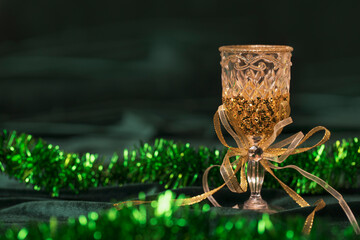 Christmas toy - a crystal wine glass with a gold bow on a green velvet fabric with tinsel....