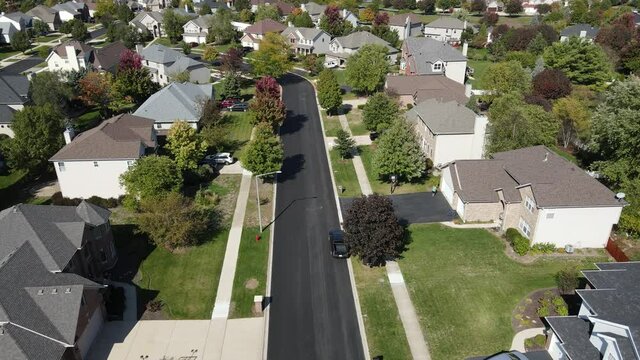 Overhead aerial view of colorful autumn trees residential houses and yards along suburban street in Chicago area. Midwest USA. 4K