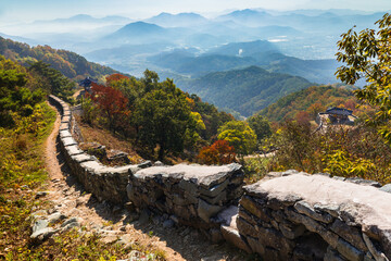 Beautiful Korean autumn scenery. Colorful autumn leaves seen from the top of the mountain and traditional buildings along the castle road. Jeollanam-do, Geumseongsanseong, South Korea.