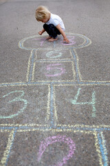 Child, blond boy, playing hopscotch on the street