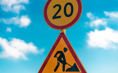 Close up of sign of road work on background of blue sky with white clouds. Information for traffic...