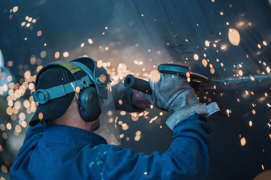 Worker cutting steel tanks with flying sparks