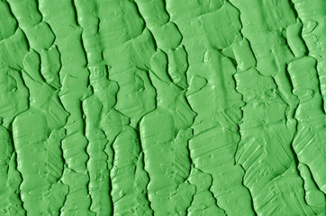 Green cosmetic clay (cucumber facial mask, avocado face cream, green tea matcha body wrap) texture close up, selective focus. Abstract background with brush strokes.