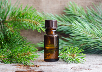 Small bottle with essential pine oil (extract, tincture, infusion). Old wooden background. Aromatherapy, spa and herbal medicine concept. Copy space.
