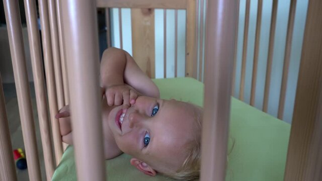 Cute baby boy child in diapers lying in bed. Child look at camera. Gimbal motion