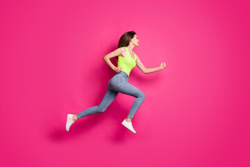 Fototapeta na wymiar Full body profile side photo of girl jump run fast look empty space wear casual outfit jeans isolated over pink color background