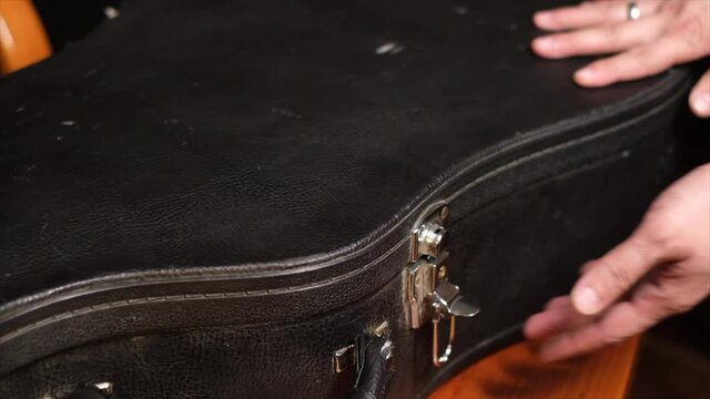 Close frame of male hands closing guitar case   