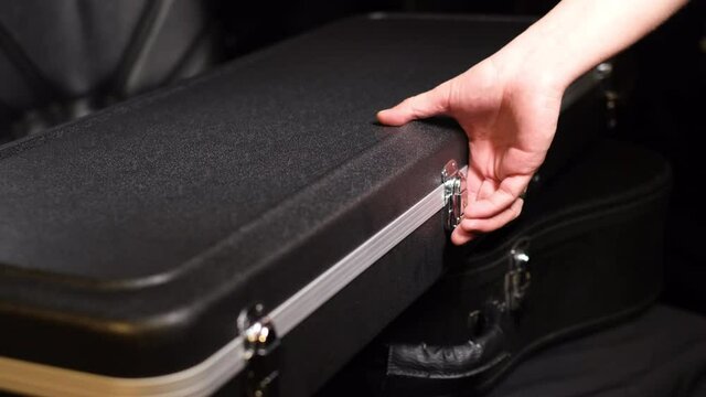 Close frame of male hands closing guitar case   