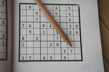 sudoku (crossword) puzzle and pencil. Selective focus.