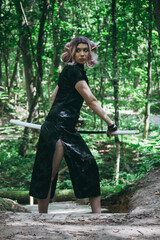 An elven girl with a katana in her hands is walking through the forest and preparing for battle