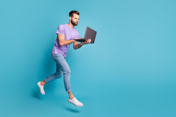 Full length body size photo of focused jumping man typing working on laptop isolated on bright blue color background