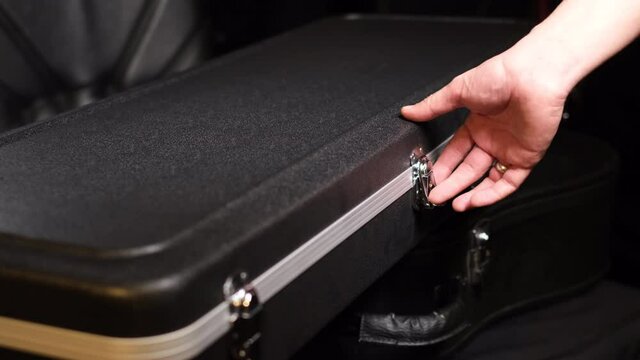 Close frame of male hands opening guitar case