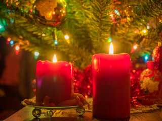 Two candles and Christmas decorations, on green background. Soft focus.