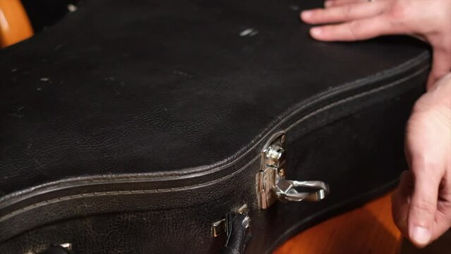 Close frame of male hands opening guitar case