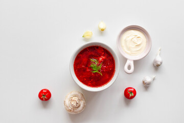 Top view of the traditional Ukrainian borscht or soup with beets, potatoes, tomatoes, meat in bowls on a white background. Top view. Free copy space.