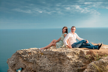 Young married couple admires the sea or ocean at edge of a rocky cliff. Family photoshoot on...