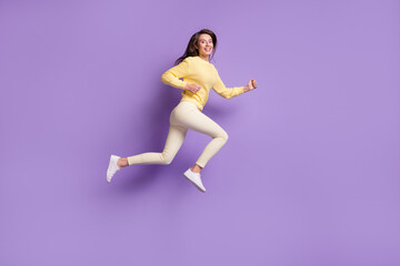Fototapeta na wymiar Full length photo portrait of woman running smiling jumping up isolated on bright purple colored background