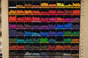 Naklejka premium Color palette. Multi-colored pencils on a shelf in a bookstore. Goods for creativity and drawing.