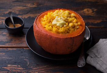 Sweet pumpkin rice with butter baked  in pumpkin pot on a wooden table. delicious seasonal homemade breakfast