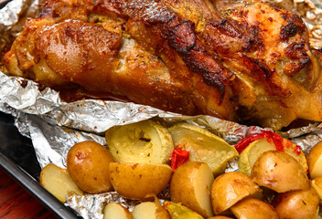 baked meat and potatoes on a baking sheet, pork knuckle delicious food
