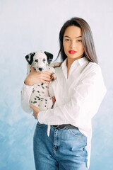 Woman stands with puppy of dalmatian dog.