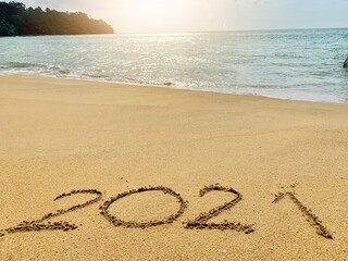 Welcome new year 2021 Write on the sand by the sea, near the sunset.