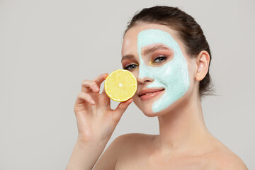 Portrait of a beautiful woman with a blue cream mask on her face and a slice of lemon. Close-up