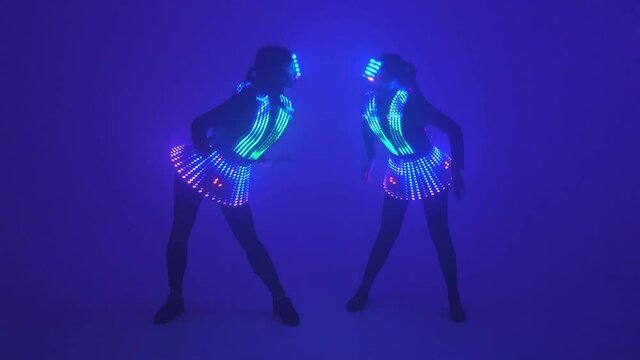 Two sexy female disco dancers moving in UV costumes