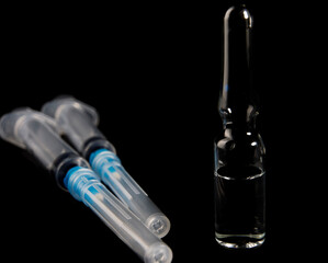 Syringes and a drug vial on a black background. Vaccine.