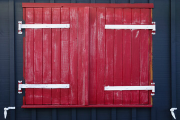Closed red shutters on a dark blue wooden cabin, oyster-farming's shed, France